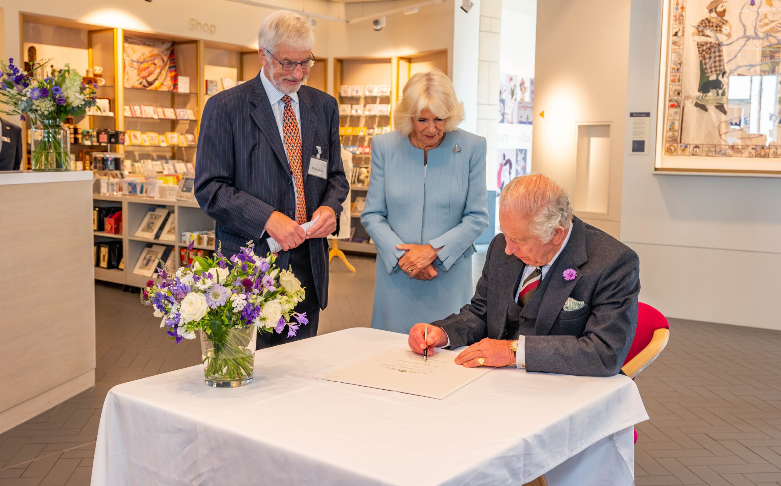 Their Majesties sign a commemorative certificate that will be hung alongside the commemorative panel in the Centre