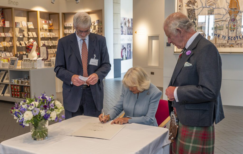 Their Majesties sign a commemorative certificate that will be hung alongside the commemorative panel in the Centre